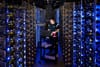 A Google Cloud worker diagnoses a problem in the middle of a large rack of servers.