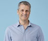 A headshot of Canva CTO Brendan Humphreys wearing a blue and white shirt.