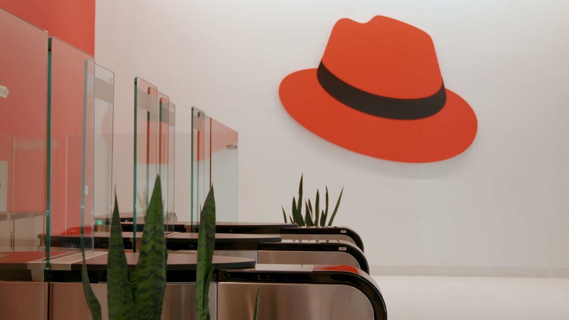 The lobby of Red Hat's headquarters building with badged entry gates and a big red hat.